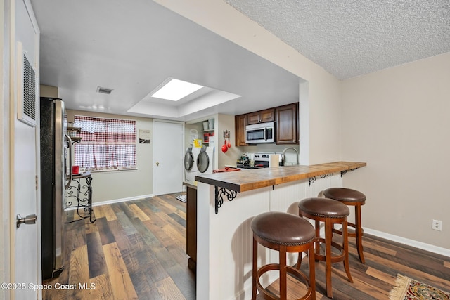 1515 Huntington Ln Unit 227, Rockledge, FL 32955 - kitchen with stainless steel microwave, independent washer and dryer, range with electric stovetop, a breakfast bar, and dark wood-type flooring
