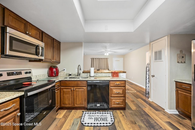 1515 Huntington Ln Unit 227, Rockledge, FL 32955 - kitchen with stainless steel appliances, a raised ceiling, a peninsula, light wood-type flooring, and light stone counters