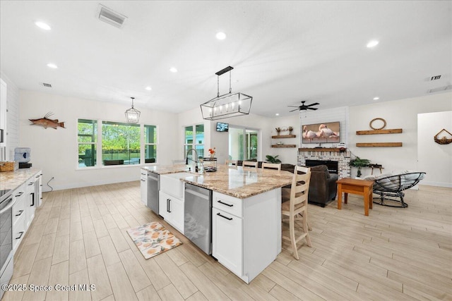 6190 Brabrook Ave, Grant, FL 32949 - kitchen featuring appliances with stainless steel finishes, light wood-style floors, a ceiling fan, a fireplace, and white cabinetry