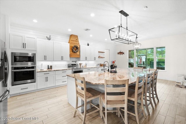 6190 Brabrook Ave, Grant, FL 32949 - kitchen featuring stainless steel appliances, white cabinetry, light stone countertops, a chandelier, and light wood finished floors