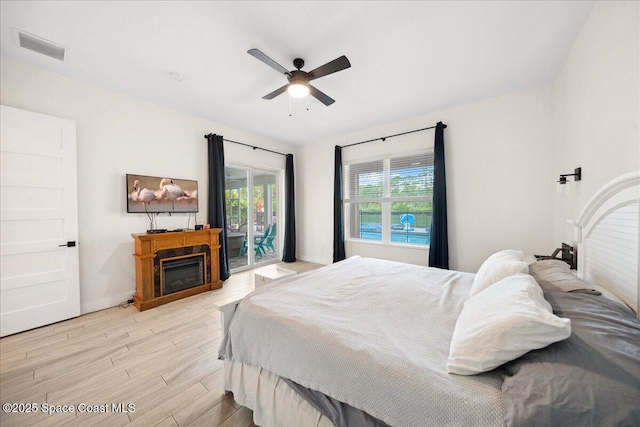 6190 Brabrook Ave, Grant, FL 32949 - bedroom with access to outside, light wood-style flooring, a ceiling fan, and a glass covered fireplace