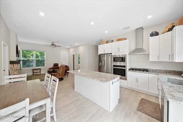 6190 Brabrook Ave, Grant, FL 32949 - kitchen featuring appliances with stainless steel finishes, wall chimney range hood, a kitchen island, light stone countertops, and recessed lighting