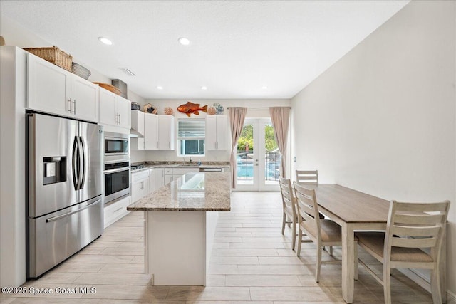 6190 Brabrook Ave, Grant, FL 32949 - kitchen featuring stainless steel appliances, a kitchen island, light stone counters, white cabinets, and french doors