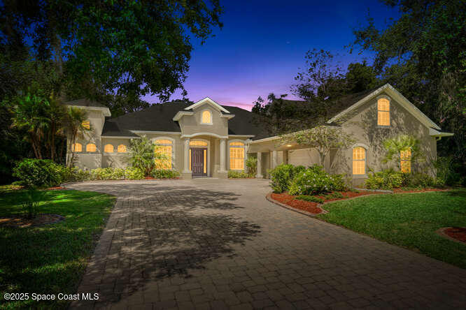 4356 Davidia Dr, Melbourne, FL 32934 - view of front of house featuring decorative driveway, an attached garage, a front lawn, and stucco siding