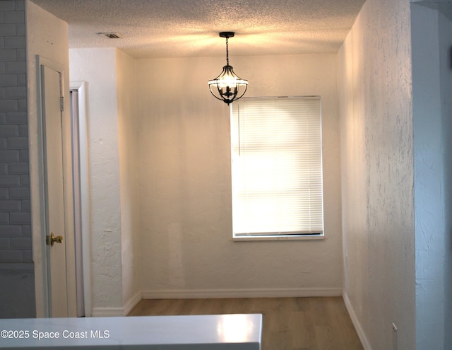 1001 Bernice Rd, Rockledge, FL 32955 - unfurnished dining area with wood finished floors, a textured ceiling, and a chandelier