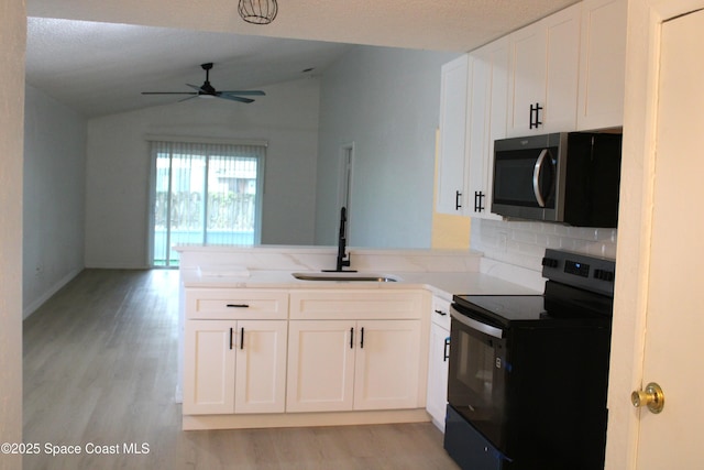 1001 Bernice Rd, Rockledge, FL 32955 - kitchen featuring black range with electric stovetop, stainless steel microwave, vaulted ceiling, ceiling fan, and light wood-style flooring