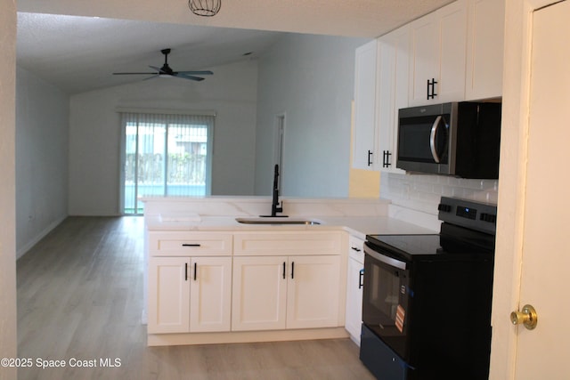 1001 Bernice Rd, Rockledge, FL 32955 - kitchen featuring black electric range, stainless steel microwave, a ceiling fan, light wood finished floors, and vaulted ceiling