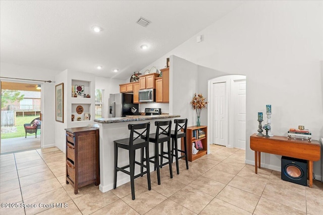5575 Hemsing St, Cocoa, FL 32927 - kitchen with appliances with stainless steel finishes, lofted ceiling, light tile patterned flooring, arched walkways, and a breakfast bar area