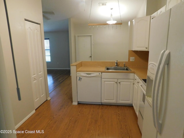 1679 Cardinal Ct, Melbourne, FL 32935 - kitchen featuring white appliances, white cabinetry, light wood-style flooring, a peninsula, and decorative light fixtures