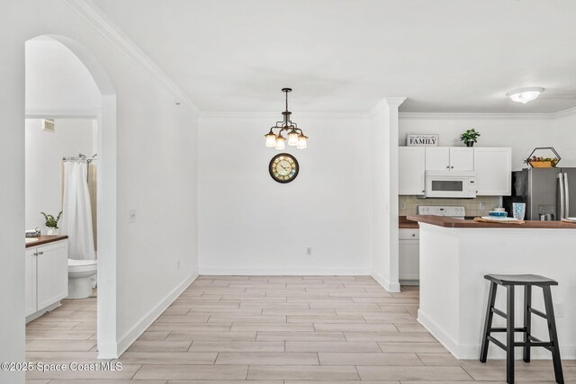 6461 Borasco Dr Unit 3808, Melbourne, FL 32940 - kitchen featuring white microwave, freestanding refrigerator, white cabinets, light wood-style floors, and crown molding