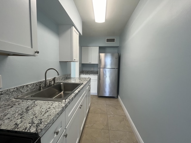 250 N Banana River Dr Unit F-11, Merritt Island, FL 32952 - kitchen with freestanding refrigerator, light tile patterned flooring, and white cabinetry