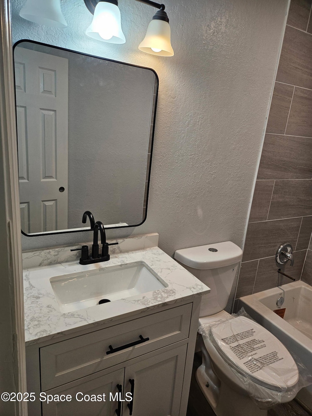 2062 E Cedarwood Dr, Melbourne, FL 32935 - full bathroom featuring a textured wall, vanity, and shower / bathtub combination