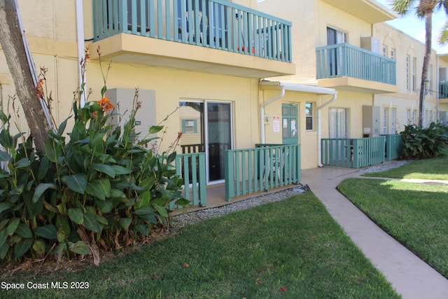 350 Taylor Ave Unit 11B2, Cape Canaveral, FL 32920 - view of exterior entry with stucco siding, a yard, and a balcony