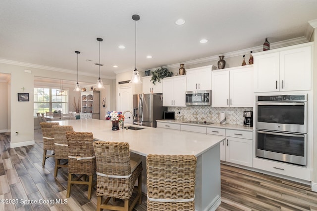 4014 Preservation Cir, Melbourne, FL 32934 - kitchen featuring stainless steel appliances, wood finished floors, backsplash, an island with sink, and white cabinetry