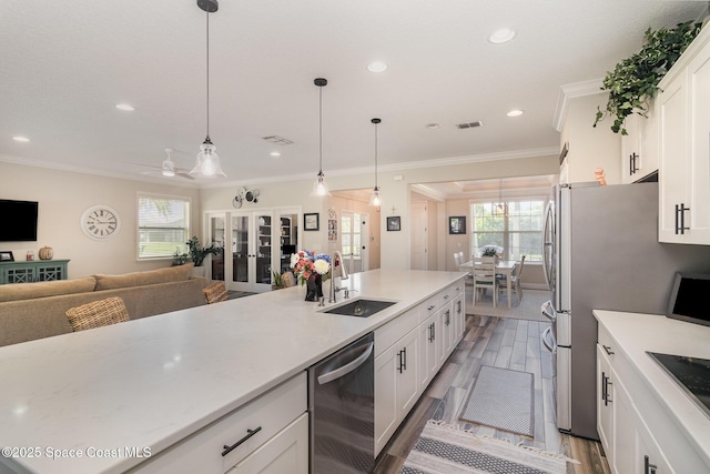 4014 Preservation Cir, Melbourne, FL 32934 - kitchen with appliances with stainless steel finishes, white cabinets, hanging light fixtures, light wood-style floors, and crown molding