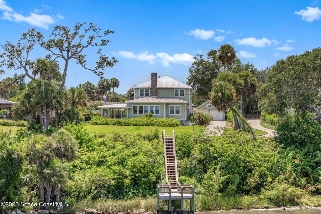 2907 N Indian River Dr, Cocoa, FL 32922 - rear view of house featuring a chimney, view of scattered trees, and a detached garage