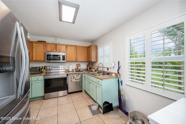 957 Stage St SE, Palm Bay, FL 32909 - kitchen featuring appliances with stainless steel finishes, light tile patterned floors, green cabinetry, a textured ceiling, and light countertops