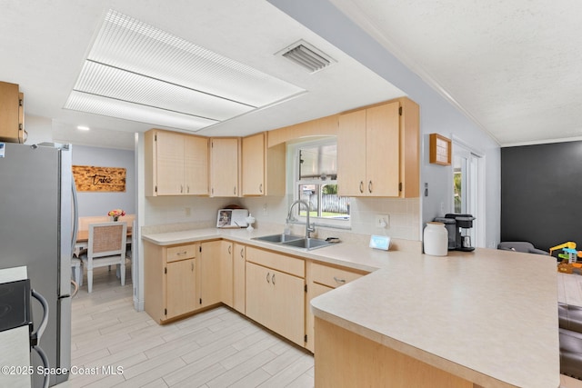 416 Catalina Ave NW, Palm Bay, FL 32907 - kitchen featuring freestanding refrigerator, a peninsula, light brown cabinets, light countertops, and ornamental molding