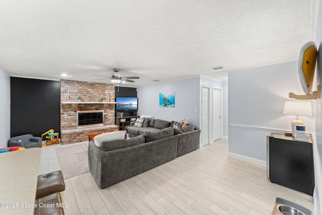 416 Catalina Ave NW, Palm Bay, FL 32907 - living room with ceiling fan, a textured ceiling, ornamental molding, a fireplace, and light wood-style floors