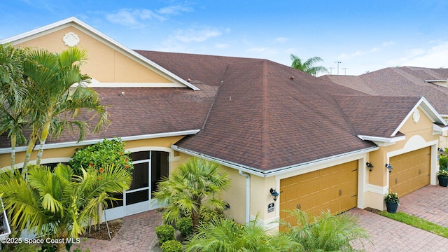 5727 Tamarac Dr, Melbourne, FL 32940 - view of front of home featuring a garage, stucco siding, roof with shingles, a sunroom, and decorative driveway