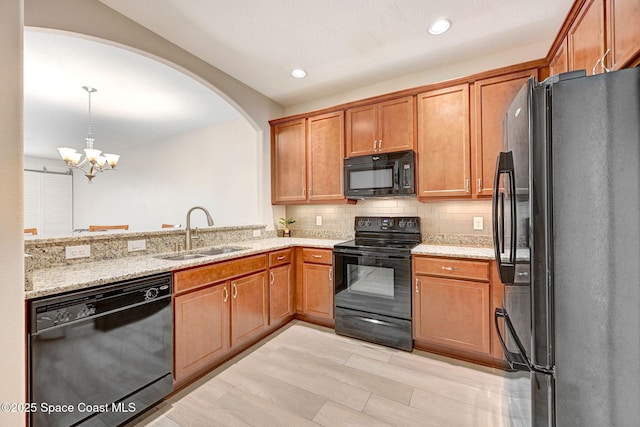 5727 Tamarac Dr, Melbourne, FL 32940 - kitchen with black appliances, light stone countertops, backsplash, a chandelier, and arched walkways