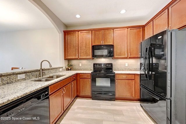 5727 Tamarac Dr, Melbourne, FL 32940 - kitchen with black appliances, light stone countertops, arched walkways, brown cabinetry, and recessed lighting