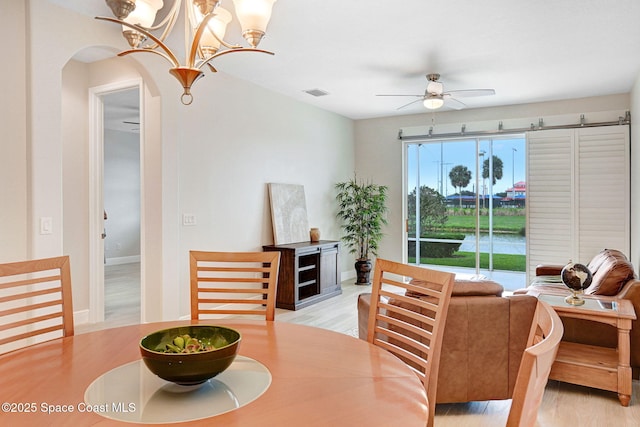 5727 Tamarac Dr, Melbourne, FL 32940 - dining space featuring arched walkways, a ceiling fan, light wood-style floors, and a chandelier