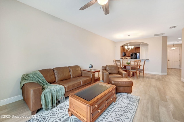 5727 Tamarac Dr, Melbourne, FL 32940 - living area featuring arched walkways, light wood-type flooring, a ceiling fan, and a chandelier