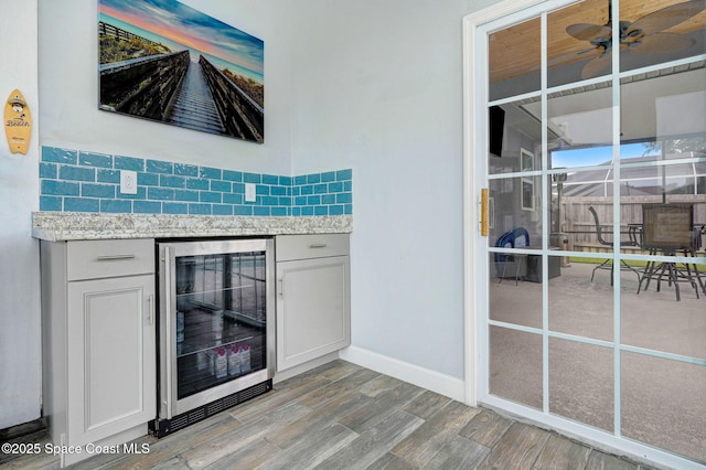 1067 Red Bud Cir, Rockledge, FL 32955 - bar area featuring beverage cooler, light wood-type flooring, a ceiling fan, and decorative backsplash
