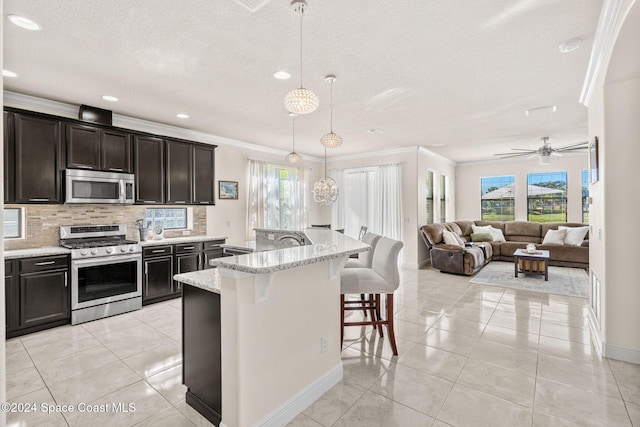 8522 Strom Park Dr, Melbourne, FL 32940 - kitchen featuring appliances with stainless steel finishes, ornamental molding, a textured ceiling, a kitchen bar, and plenty of natural light