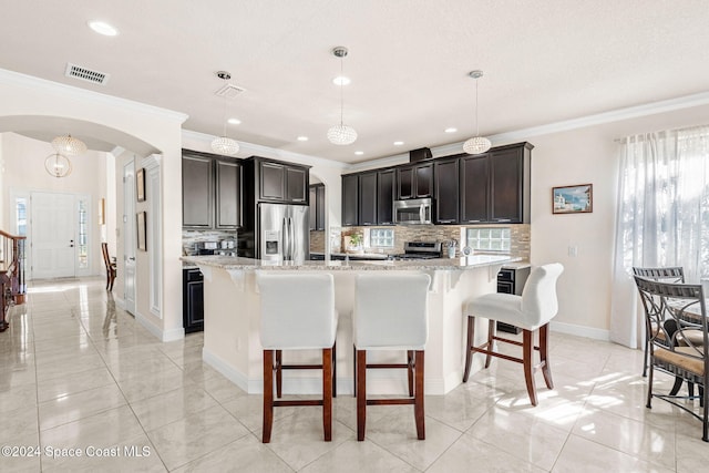 8522 Strom Park Dr, Melbourne, FL 32940 - kitchen featuring appliances with stainless steel finishes, arched walkways, ornamental molding, a breakfast bar area, and backsplash