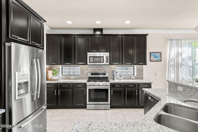 8522 Strom Park Dr, Melbourne, FL 32940 - kitchen with appliances with stainless steel finishes, dark cabinets, ornamental molding, tasteful backsplash, and light tile patterned floors