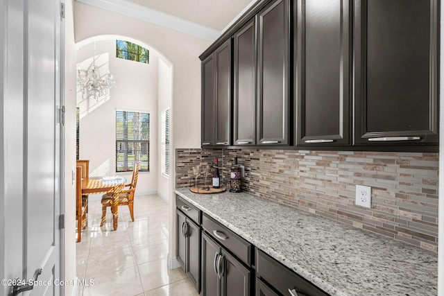 8522 Strom Park Dr, Melbourne, FL 32940 - kitchen featuring ornamental molding, tasteful backsplash, arched walkways, light stone countertops, and light tile patterned floors