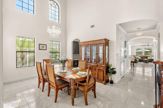 8522 Strom Park Dr, Melbourne, FL 32940 - dining area featuring arched walkways, ornamental molding, a high ceiling, a chandelier, and light marble finish flooring