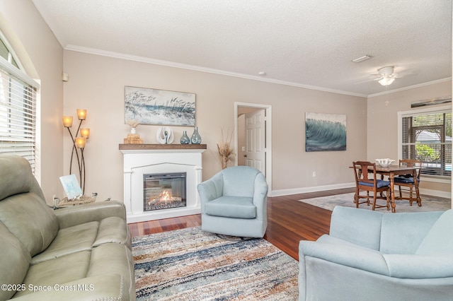 1510 Gardenton St NW, Palm Bay, FL 32907 - living area featuring wood finished floors, crown molding, a glass covered fireplace, a textured ceiling, and a ceiling fan