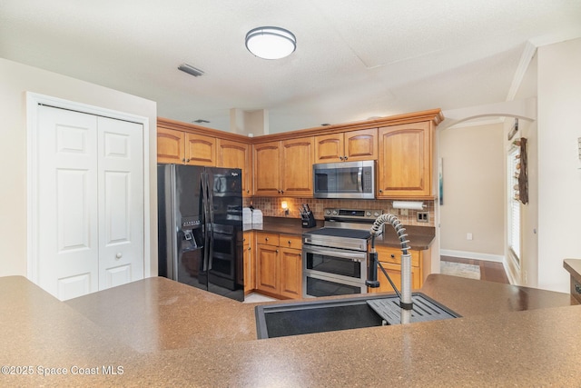 1510 Gardenton St NW, Palm Bay, FL 32907 - kitchen featuring appliances with stainless steel finishes, decorative backsplash, arched walkways, dark countertops, and brown cabinets