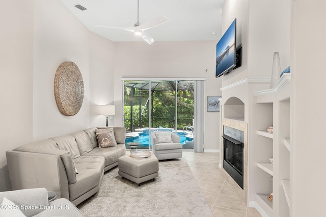 172 Whaler Dr, Melbourne Beach, FL 32951 - living room featuring a ceiling fan, built in shelves, light tile patterned floors, a towering ceiling, and a tiled fireplace