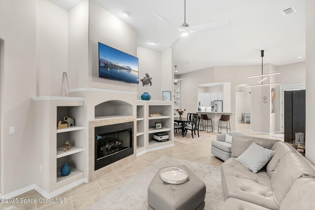 172 Whaler Dr, Melbourne Beach, FL 32951 - living room with a ceiling fan, light tile patterned floors, built in shelves, a tiled fireplace, and arched walkways