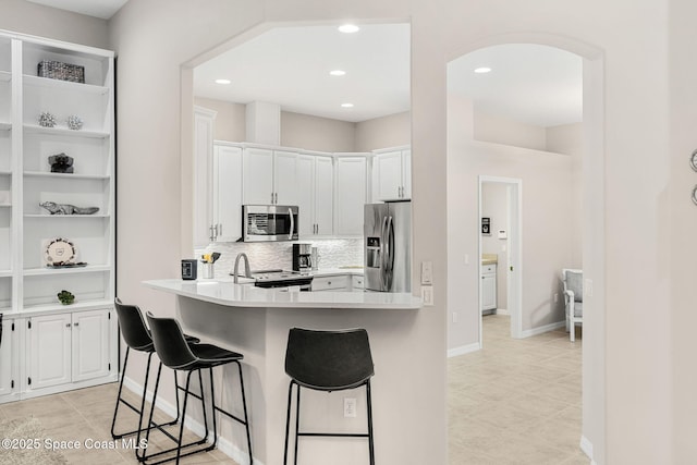 172 Whaler Dr, Melbourne Beach, FL 32951 - kitchen with appliances with stainless steel finishes, a breakfast bar, white cabinets, backsplash, and light countertops