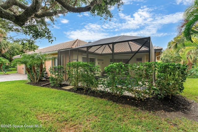 172 Whaler Dr, Melbourne Beach, FL 32951 - view of side of property with stucco siding, an attached garage, a yard, driveway, and glass enclosure