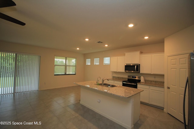 947 Remington Green Dr SE, Palm Bay, FL 32909 - kitchen featuring stainless steel appliances, recessed lighting, tile patterned floors, light stone countertops, and an island with sink