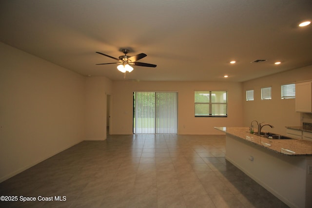 947 Remington Green Dr SE, Palm Bay, FL 32909 - kitchen with white cabinetry, recessed lighting, light stone counters, open floor plan, and a ceiling fan