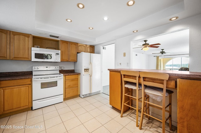 1727 Minutemen Cswy Unit 108, Cocoa Beach, FL 32931 - kitchen featuring white appliances, recessed lighting, dark countertops, brown cabinetry, and a tray ceiling