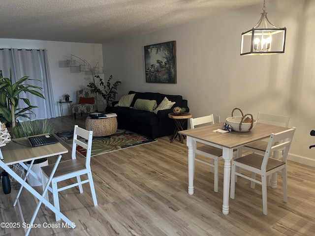 3799 S Banana River Blvd Unit 104, Cocoa Beach, FL 32931 - dining room with light wood finished floors, a textured ceiling, and a chandelier