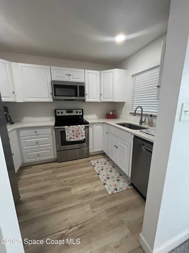 3799 S Banana River Blvd Unit 104, Cocoa Beach, FL 32931 - kitchen with appliances with stainless steel finishes, white cabinets, light wood finished floors, and light countertops