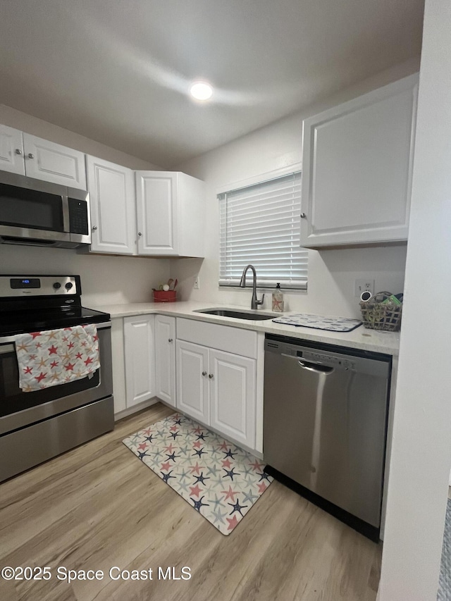 3799 S Banana River Blvd Unit 104, Cocoa Beach, FL 32931 - kitchen with stainless steel appliances, light wood-style floors, white cabinetry, and light countertops