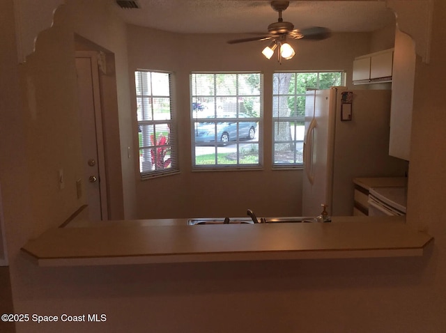 33 Kings Colony Ct, Palm Coast, FL 32137 - kitchen with range, ceiling fan, white cabinets, freestanding refrigerator, and light countertops