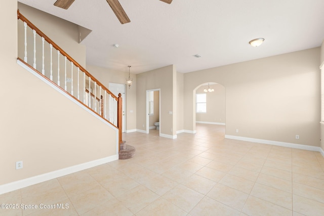 2032 Elkins Pt, Melbourne, FL 32935 - unfurnished living room featuring ceiling fan, stairs, light tile patterned floors, arched walkways, and a chandelier