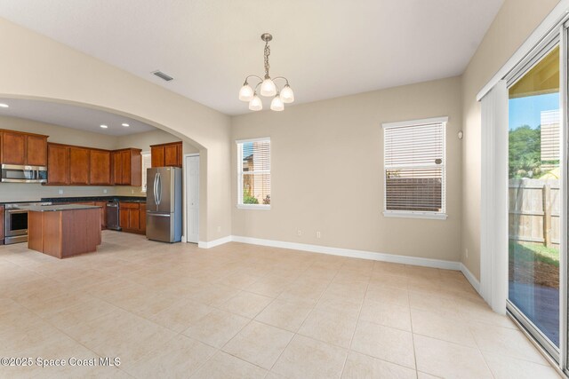 2032 Elkins Pt, Melbourne, FL 32935 - kitchen with stainless steel appliances, a chandelier, light tile patterned flooring, brown cabinets, and open floor plan
