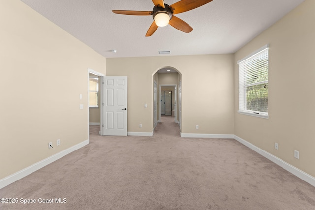 2032 Elkins Pt, Melbourne, FL 32935 - empty room featuring arched walkways, ceiling fan, light carpet, and a textured ceiling